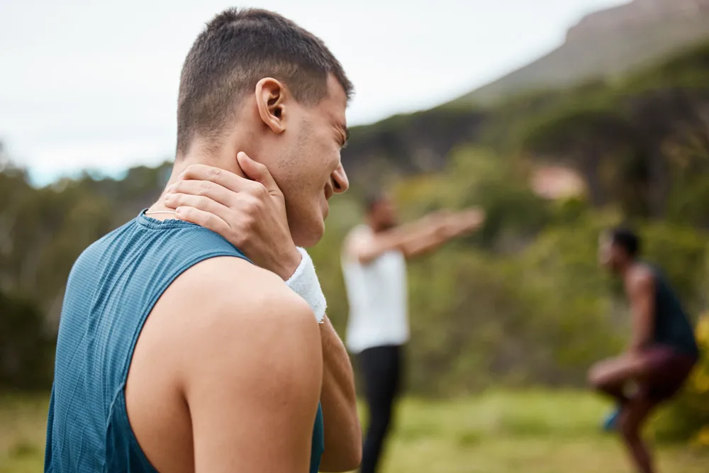 there is a man with a neck pain standing in a field