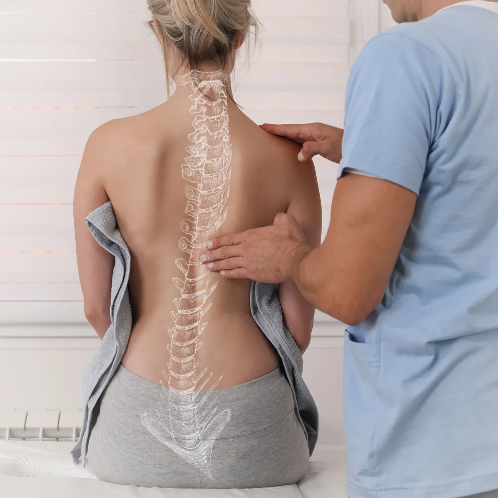 woman with a back pain sitting on a table while a man holds her